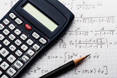 Taschenrechner auf einem mit mathematischen Formeln beschriebenen Blatt Papier
