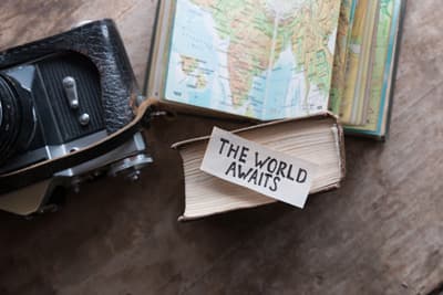 Karte, Fotoapparat und ein Schild "The World Awaits"