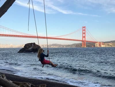Studentin schaukelt vor der Golden Gate Bridge