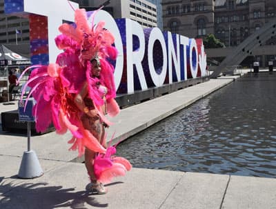 Eine Frau in rotem Federschmuck vor Buchstaben, die Toronto ausschreiben