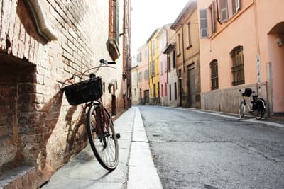 Ein Fahrrad lehnt an einer Hauswand in einer kleinen italienischen Gasse in Piacenza