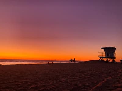 Spektakulärer orange-lilafarbener Sonnenuntergang am Strand.