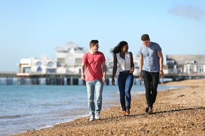 Studierende spazieren am Strand von Portsmouth entlang
