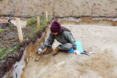 Archäologin beim Säubern und Freilegen einer Mauer