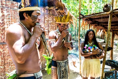 Indigene in Brasilien spielen auf hölzernen Flöten