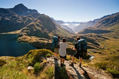 Drei Personen wandern in Neuseeland, umgeben von einer spektakulären Landschaft.