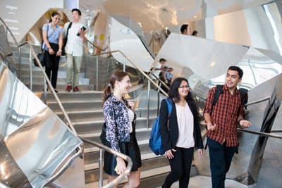 3 Studenten laufen im modernen Treppenhaus der UTS
