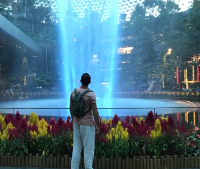 Student betrachtet Wasser-Fontäne eines Brunnens in einem Einkaufszentrum in Singapur