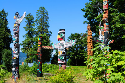 Bunte indianische Totempfähle in den kanadischen Wäldern