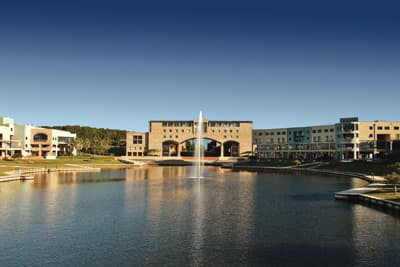 Ein Gebäude der Bond University hinter einem Teich mit einer großen Fontäne