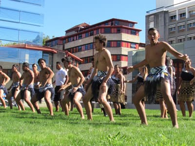 Studierende in traditioneller Maori-Kleidung vor modernen Gebäuden