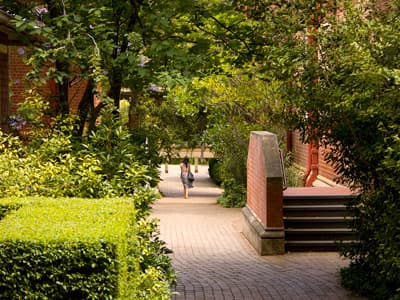 Studentin streift über den grünen Campus der University of Melbourne.