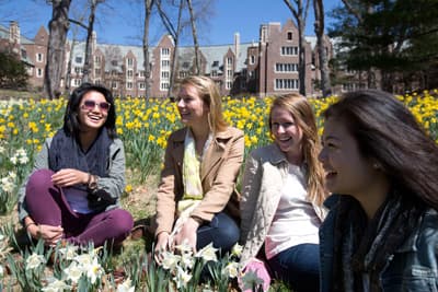 Studentinnen sitzen auf einer Wiese vor dem Wellesley College.