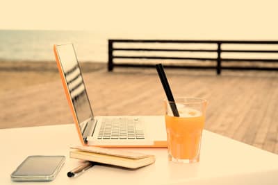 Ein Tisch auf einer Terrasse mit Laptop und sommerlichem Getränk