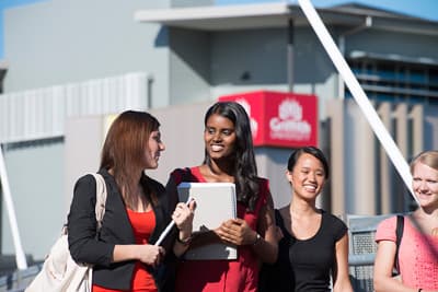 Women talking in front of a bright university building