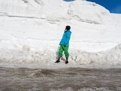 Snowboarder steht vor einer hohen Schneewand