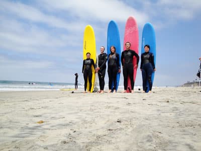 Fünf Surfer am Sandstrand