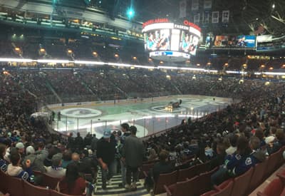 Gut gefülltes Eishockey-Stadion mit leuchtender Anzeigetafel im Zentrum.