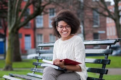 Studentin auf einer Parkbank in der Nähe des Dorset Campus.