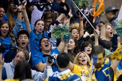 Blau und gelb gekleidete Studenten Jubeln ihren Uni-Sport-Mannschaften zu