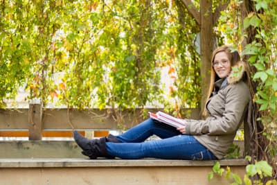 Studentin liest ein Buch in einer Laube