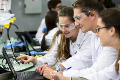 Studenten mit Schutzbrillen arbeiten an einem Computer im Labor.