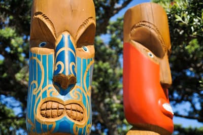 Zwei Maori-Holzschnitzereien in Form von finster dreinblickenden Kriedern