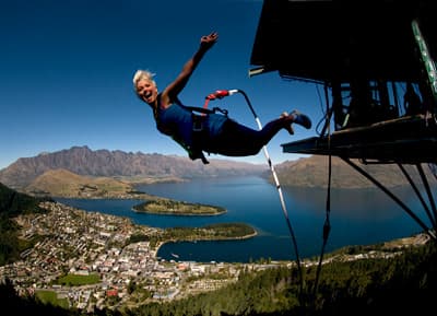 Junge Frau macht Bungee-Jumping vor wunderschönem Berg- und Seenpanorama