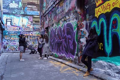 Studenten posieren in einem Laneway im Stadtzentrum Melbournes mit vielen Graffitis.