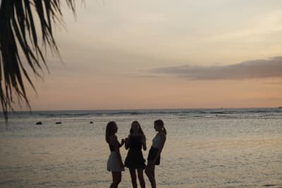 Silhouetten von drei Studentinnen am Strand kurz nach Sonnenuntergang