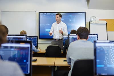 Kurs im Thomson Reuters room der Universität. Die Studierenden arbeiten an jeweils eigenen PCs, während vorne an einem großen Bildschirm erklärt wird.