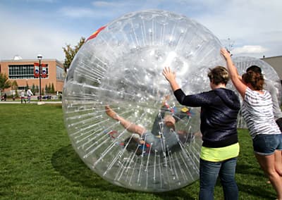 Studenten rollen sich gegenseitig in großen Luftbällen über den Campus.