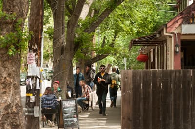 Studierende sitzen in Cafés an einer mit Bäumen gesäumten Straße in Davis