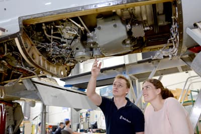Eine Studentin lässt sich den komplizierten mechanischen Aufbau eines Flugzeugs vonn innen zeigen.