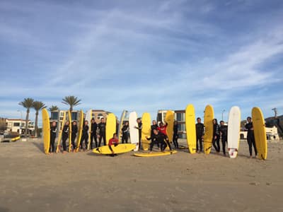 Surfer stehen mit ihrem Surfbrett in einer Reihe am Strand von San Diego