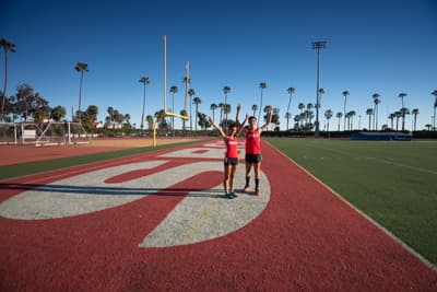 Studenten mit SBCC Kleidung auf dem Spielfeld des La Playa Stadiums. Im Hintergrund sieht man Palmen.