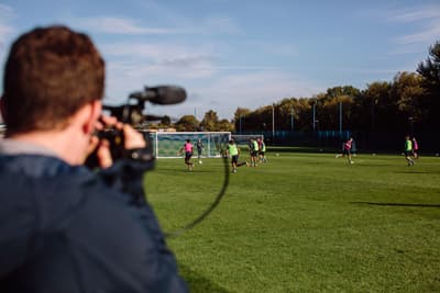 Ein Student filmt ein Fußballteam auf dem Feld.