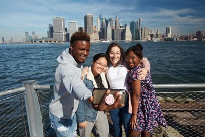 Studierende machen ein Selfie vor der Skyline Manhattans