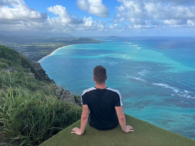 Student sitzt auf einer Aussichtsplattform und schaut auf den Ozean