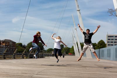 Studierende hüpfen freudig über eine Brücke in Cardiff