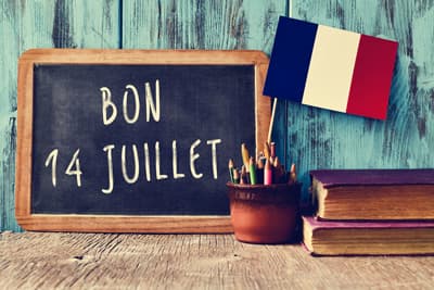 Tafel mit der Aufschrift "Bon 14 Juillet" neben der französischen Flagge