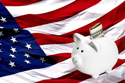 Sparschwein mit US-Dollar vor einer US-amerikanischen Flagge