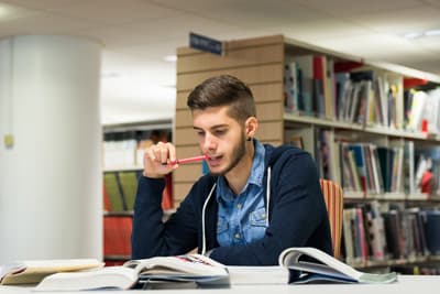 Ein junger Student lernt in einer Bibliothek.