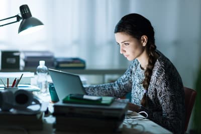 Eine junge Frau sitzt konzentriert am Laptop.