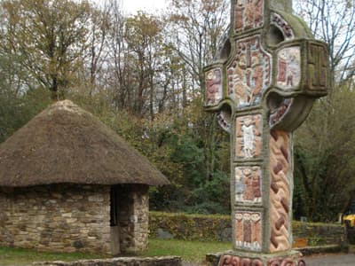 Einfaches strohbedecktes Steinhaus und keltisches Kreuz 