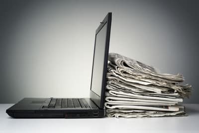 Laptop lehnt gegen einen Stapel Zeitungen