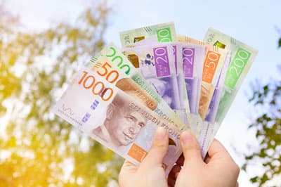 Schwedische Geldscheine werden mit zwei Händen als Fächer in den Himmel gehalten.