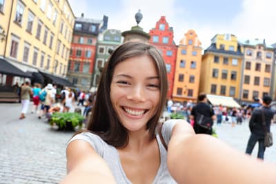Ein junges Mädchen lacht auf einem Marktplatz in Schweden in die Kamera.