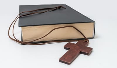 Eine Bibel mit einem Kreuz liegt auf dem Tisch.