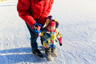 Vater hilft Kind beim Eislaufen